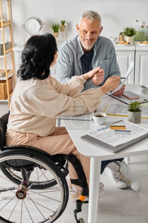 A disabled woman in a wheelchair and her caring husband planning family budget together