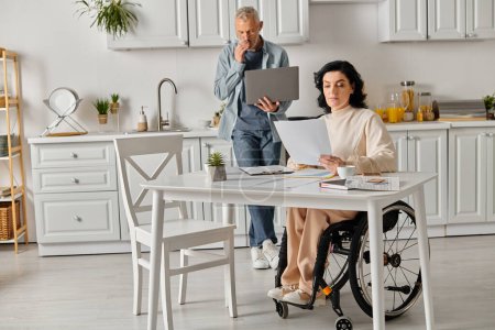 A disabled woman in a wheelchair interacts with a laptop, supported by her husband in a cozy kitchen at home.
