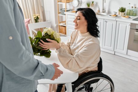 Une femme handicapée dans un fauteuil roulant tenant un bouquet vibrant de fleurs, entourée d'amour dans sa cuisine maison.