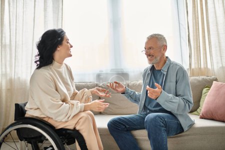 A man in a wheelchair engages in a heartfelt discussion with a disabled woman in a wheelchair in a cozy living room.