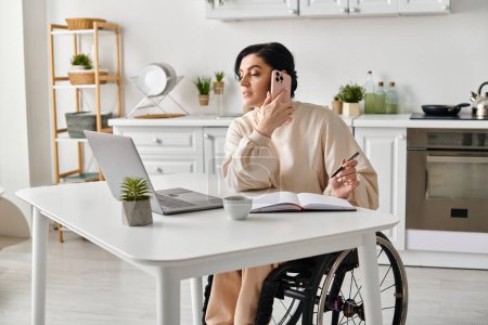 Femme en fauteuil roulant travaillant à distance, bavardant sur un téléphone portable dans la cuisine.