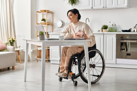 Eine Frau im Rollstuhl arbeitet konzentriert und produktiv an einem Tisch in ihrer Küche.