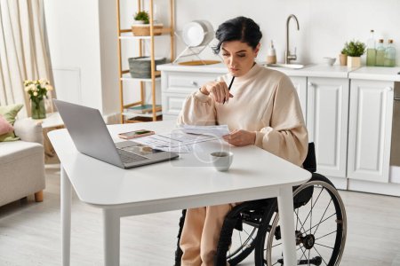 Une femme handicapée en fauteuil roulant travaille sur un ordinateur portable dans sa cuisine, faisant preuve d'indépendance et d'adaptabilité.