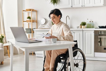 A disabled woman in a wheelchair working remotely on a laptop from her kitchen.