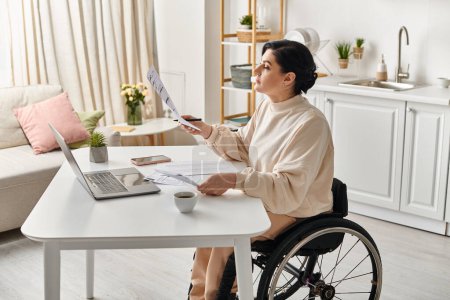 Una mujer discapacitada en una silla de ruedas que trabaja en una computadora portátil en su cocina, mostrando empoderamiento y avance tecnológico.