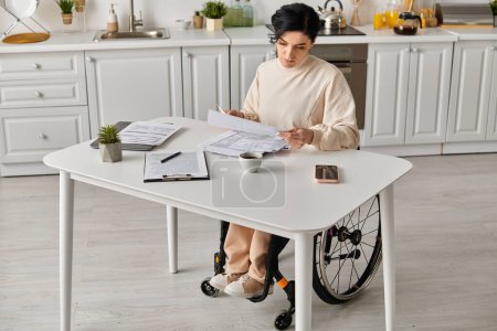 Una mujer en silla de ruedas, sentada en una mesa, absorta en leer un pedazo de papel en su cocina.
