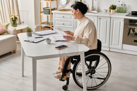Una mujer discapacitada en una silla de ruedas que trabaja a distancia en una mesa de cocina.