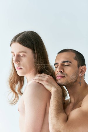 Shirtless man holding another man shoulder, conveying affection.