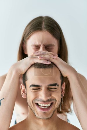 A man with a beaming smile having his boyfriends hands to his head.