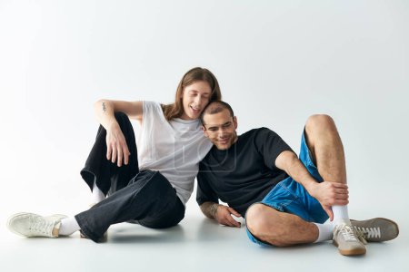 Téléchargez les photos : Deux hommes assis sur le sol, partageant un moment d'amour. - en image libre de droit