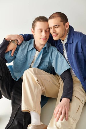 Zwei junge Männer sitzen eng beieinander und teilen einen Moment der Verbundenheit.