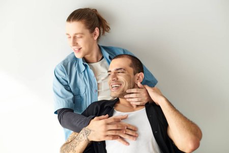Foto de Un hombre sonríe mientras sostiene a otro hombre hombro amorosamente. - Imagen libre de derechos