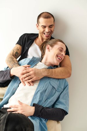 A man lovingly hugs another man on the back of a chair.