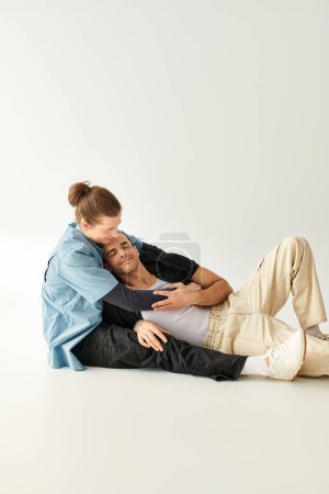Téléchargez les photos : Deux hommes amoureux assis par terre dans un cadre serein. - en image libre de droit