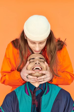 Foto de Joven abrazando a sus novios cabeza sobre fondo naranja. - Imagen libre de derechos
