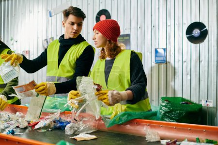 Photo for Young volunteers in gloves and safety vests work together to sort trash in a room, showing their eco-consciousness. - Royalty Free Image