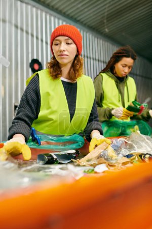 Photo for Two young volunteers in gloves and safety vests stand side by side, sorting trash together in support of a sustainable future. - Royalty Free Image