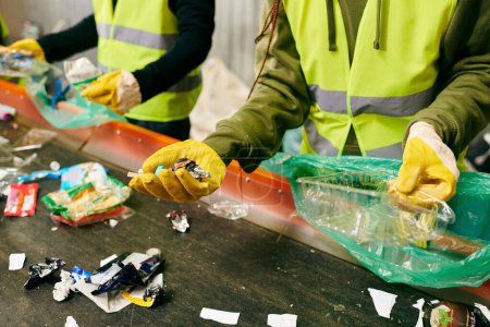 Foto de Group of eco-conscious young volunteers in yellow safety vests cleaning a table together, sorting trash. - Imagen libre de derechos