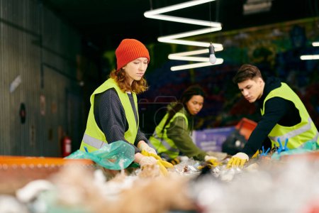Foto de A group of young volunteers in gloves and safety vests stand around a table filled with an abundance of fresh, healthy food. - Imagen libre de derechos