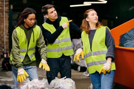 Group of young volunteers in gloves and safety vests sorting through a pile of garbage together.