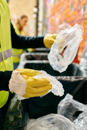 Foto de A young volunteer in a yellow safety vest and gloves sorting trash, embodying eco-consciousness. - Imagen libre de derechos