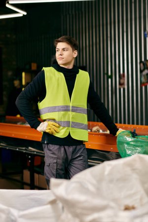 A young volunteer in gloves and safety vest sorting waste in a warehouse.