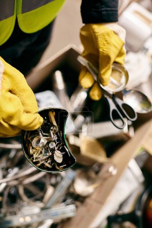 A young volunteer in yellow gloves cuts with scissors while sorting waste for recycling.