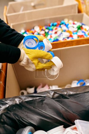 Photo for A young volunteer in gloves and safety vest holding plastic while sorting waste, staying eco conscious. - Royalty Free Image