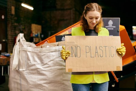 A young volunteer in gloves and safety vest holding a sign that reads no plastic at a waste sorting event.