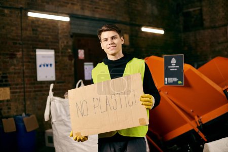Téléchargez les photos : A young volunteer in gloves and safety vest holds a sign that says no plastic at a waste sorting event. - en image libre de droit