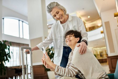 Photo for Senior lesbian couple in hotel lobby. - Royalty Free Image