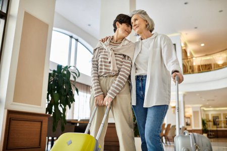 Senior lesbian couple, tenderly holding suitcases, ready for their journey.