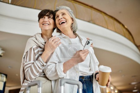 Photo for A senior lesbian couple standing together with tender affection in a hotel setting. - Royalty Free Image