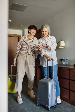 Two senior lesbian partners standing next to each other with luggage.