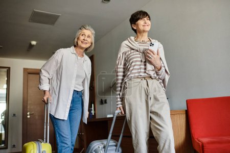 Photo for A senior lesbian couple embraces next to their luggage. - Royalty Free Image