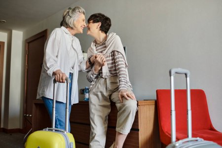 Senior lesbian couple stands with luggage, preparing for a journey ahead.