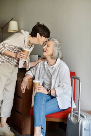 Senior lesbian couple spending time with love and tenderness while seated in a chair.
