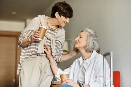 Foto de Una mujer se sienta al lado de otra sosteniendo una taza de café. - Imagen libre de derechos