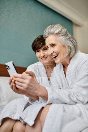 Senior lesbian couple share a tender moment on a cozy bed.
