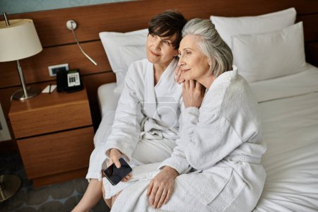 Ein zarter Moment, als ein älteres lesbisches Paar die Liebe auf einem Bett teilt.
