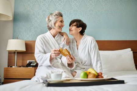 Photo for Senior lesbian couple enjoying a tender moment on top of a cozy bed. - Royalty Free Image