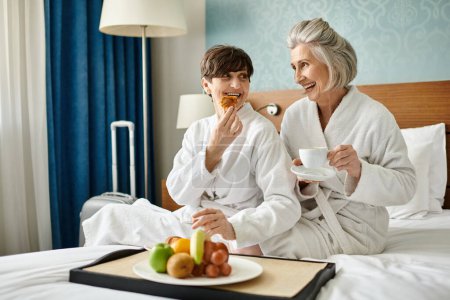 Couple de femmes âgées assis confortablement sur un lit.