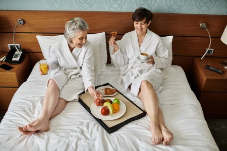 Senior pareja de lesbianas tomando el sol en tierno amor y afecto en una acogedora cama.