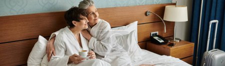 Photo for Loving senior lesbian couple enjoys a peaceful moment sitting on the bed. - Royalty Free Image