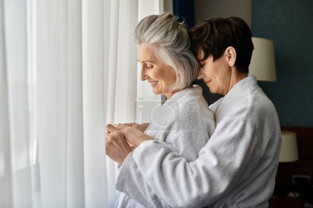 Photo for Senior lesbian couple share a quiet moment by the window. - Royalty Free Image