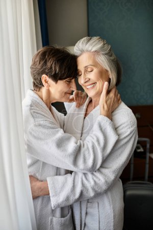 Tender moment as older woman embraces her partner in hotel.
