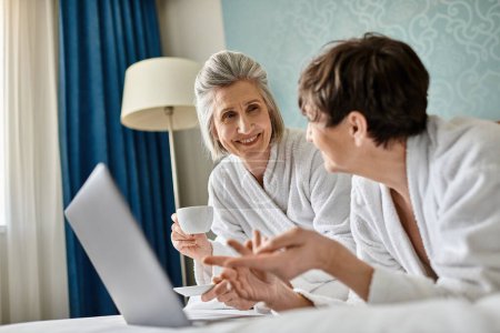 Téléchargez les photos : Un couple de lesbiennes âgées partageant une conversation dans une chambre d'hôtel confortable. - en image libre de droit