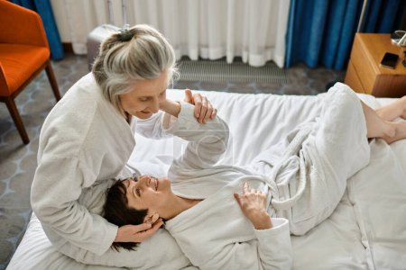 Téléchargez les photos : Senior lesbienne couple tendrement couché ensemble sur un lit. - en image libre de droit