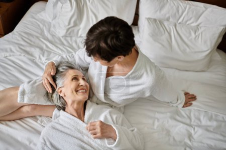 Senior lesbian couple share tender moment on bed.
