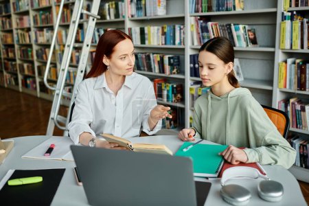 Ein rothaariger Tutor, der ein Teenager-Mädchen in einer Bibliothek nach der Schule mit einem Laptop für moderne Bildung unterrichtet.